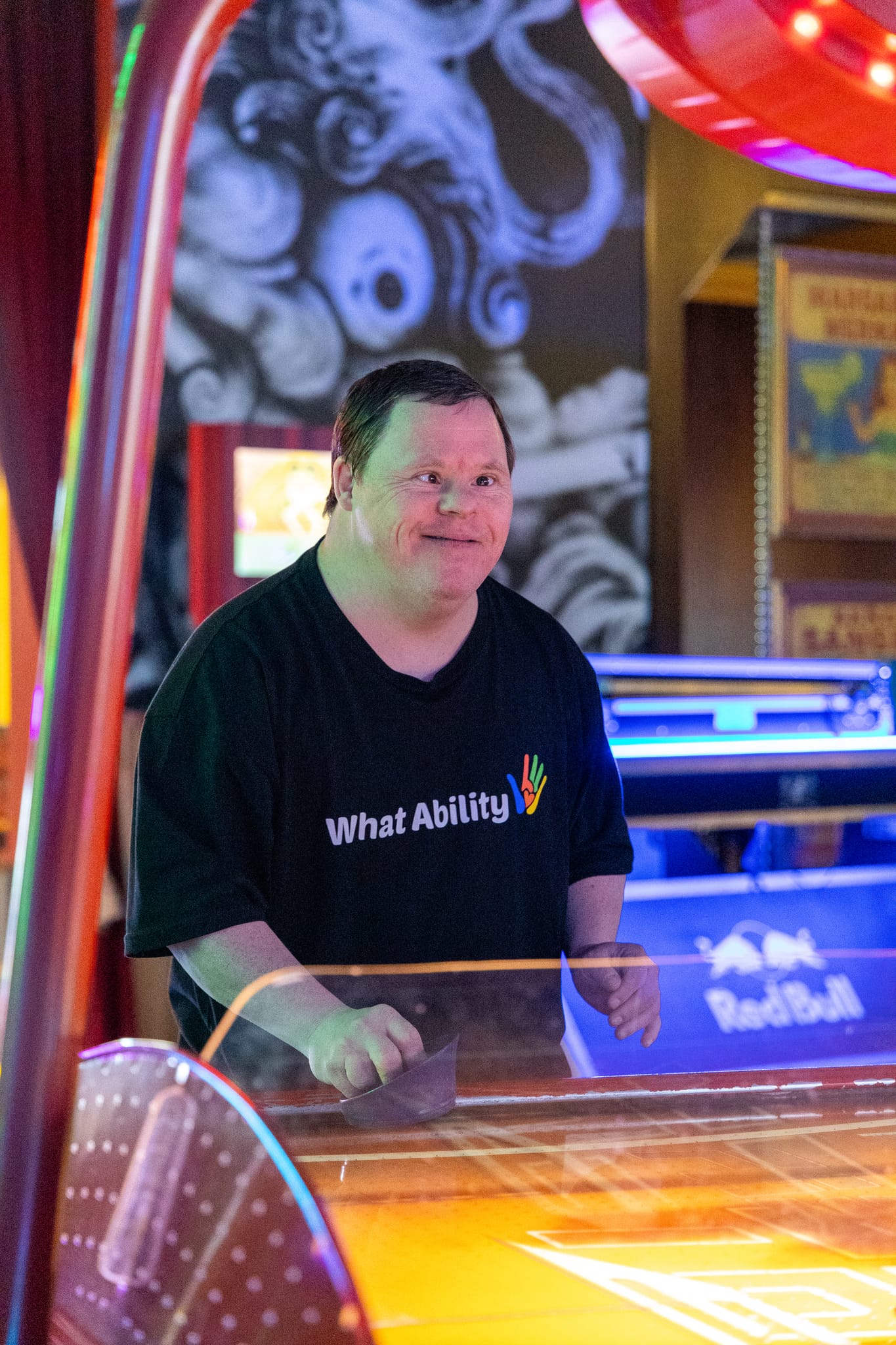 A What Ability participant playing air hockey at an arcade
