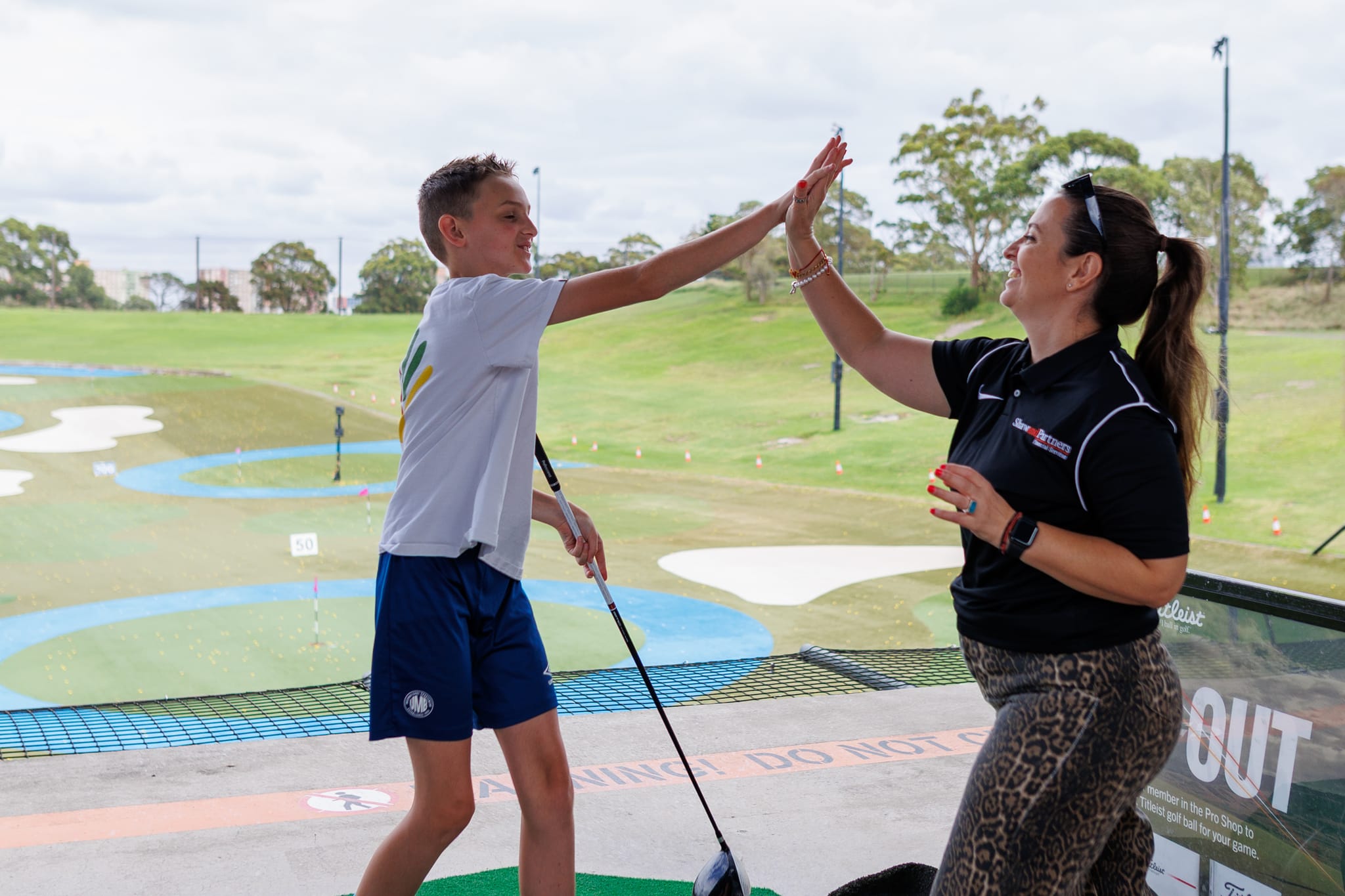 A What Ability participant high-fiving a volunteer at a golf driving range