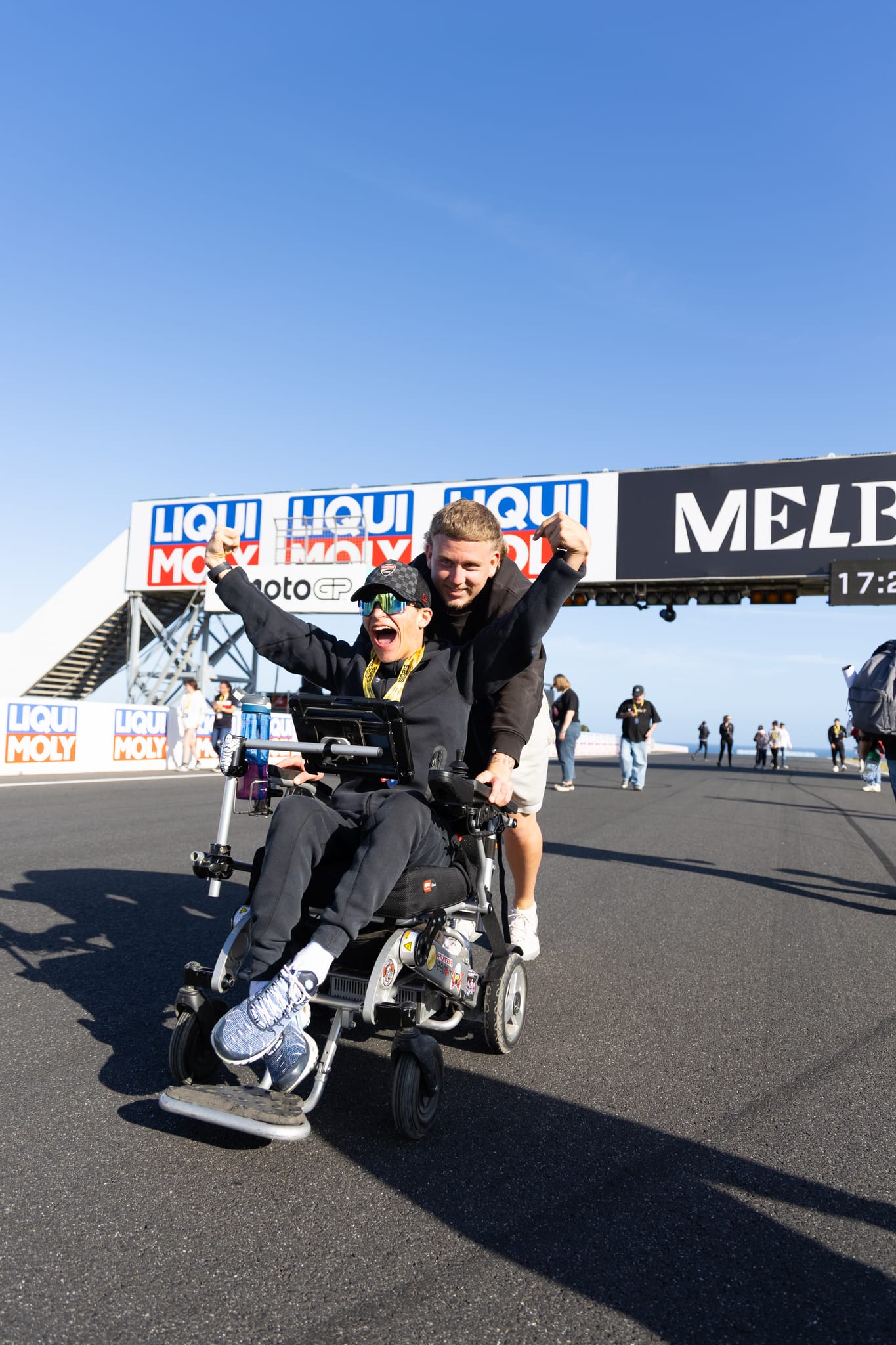 A What Ability participant using a powerchair celebrates trackside at the Australian MotoGP