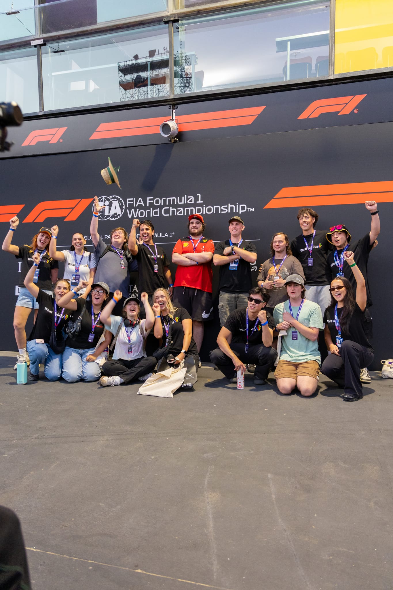 A large group of What Ability participants and volunteers celebrating together at a Formula 1 event